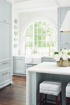 a large kitchen with blue cabinets and white counter tops, along with two stools in front of the island