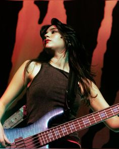 a woman with long hair playing a bass guitar