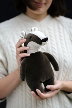 a woman holding a small stuffed animal in her right hand and wearing a white sweater