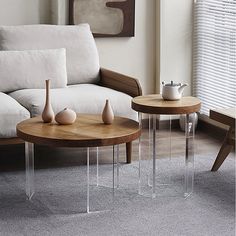 two tables sitting on top of a carpeted floor next to a couch and window