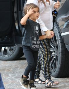 a woman and child walking next to a car