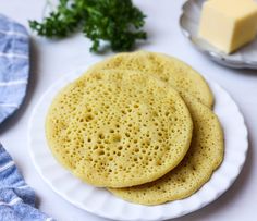 two flat breads on a white plate next to butter and parmesan cheese