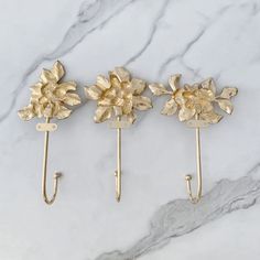 three gold flower hooks on a marble surface