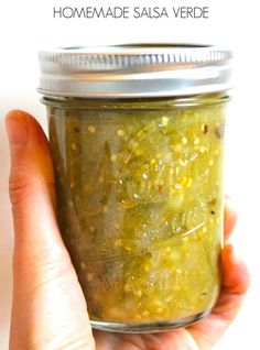 a person holding a jar filled with pickles