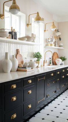 a kitchen with black cabinets and gold pulls on the doors, white counter tops and brass handles