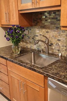 a kitchen sink with granite counter tops and wooden cabinets