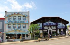 two buildings on the side of the road with people standing outside and looking at them