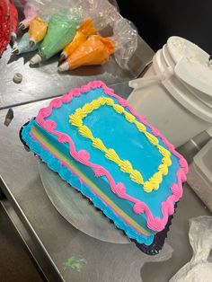 a blue and yellow cake sitting on top of a metal counter next to toilet paper