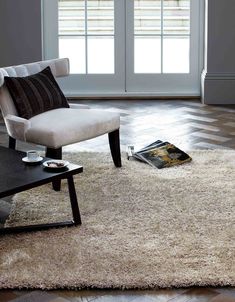 a white chair sitting on top of a rug in a living room next to a coffee table