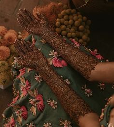 a woman's hands and feet covered in henna are sitting on the ground