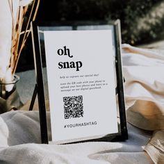 a qr code sign sitting on top of a white cloth next to a potted plant