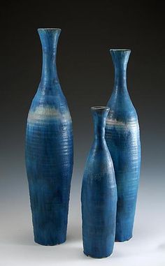 three blue vases sitting next to each other on a table