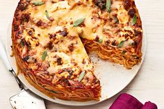 a pizza with cheese and sauce on a plate next to a fork, knife and napkin