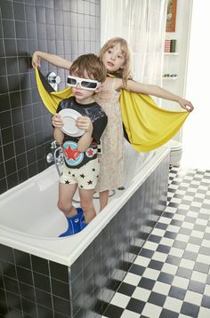 two young children standing in a bathtub with their arms around each other and wearing sun glasses