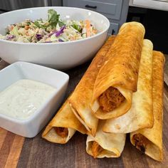 two burritos and a bowl of salad on a table