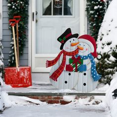 a couple of snowmen standing in front of a house