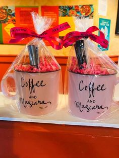 two coffee mugs are wrapped in plastic and tied with red ribbon