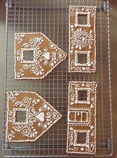 four gingerbread cutouts on a cooling rack with white frosting and decorative designs