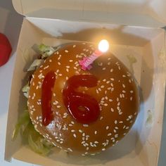 a hamburger with ketchup, lettuce and a candle