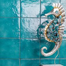 a decorative seahorse is hanging on the blue tiled wall next to a white box