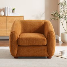 an orange chair sitting on top of a white rug next to a wooden dresser and potted plant