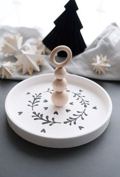 a white plate topped with a wooden ring on top of a table next to other decorations