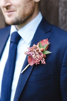 a man wearing a suit and tie with flowers on it's lapel pin