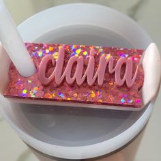 a toothbrush holder with the word clara spelled in pink glitter