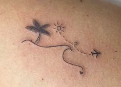 a woman's back with a small palm tree and airplane tattoo on her left shoulder