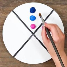 a person painting on a paper plate with paintbrushes in front of the circle