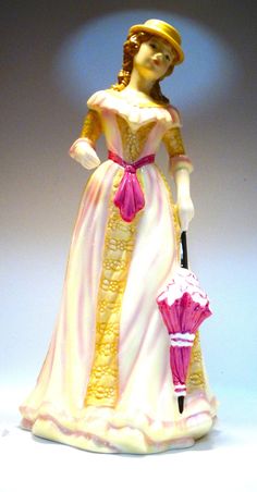 a figurine is holding an umbrella and wearing a pink dress with gold trim