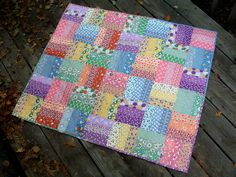 a multicolored patchwork quilt on a wooden deck