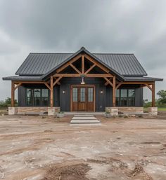 a large house with a metal roof and two doors on the front door is surrounded by dirt