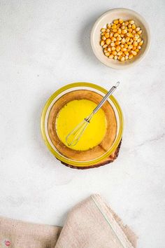 two bowls with food on them next to a whisk