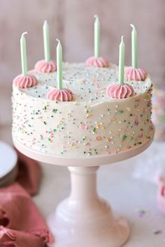 a birthday cake with white frosting and sprinkles on the top is surrounded by confetti and candles