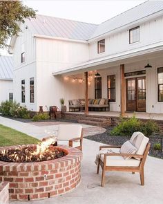 a fire pit sitting in the middle of a yard next to two chairs and a table