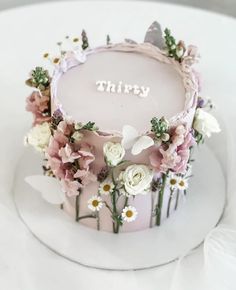 there is a cake that has flowers on it and the word thiry written in frosting