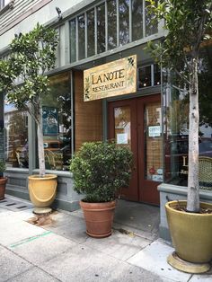 two large potted trees sit in front of the entrance to lanote's restaurant