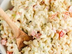 a white bowl filled with macaroni salad and a wooden spoon