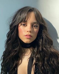 a woman with long dark hair wearing a black choker and posing for the camera