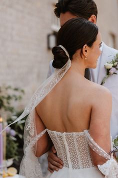 the back of a bride's wedding dress as she holds her grooms shoulder