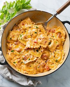 a skillet filled with macaroni and cheese on top of a marble counter