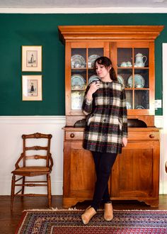 a woman standing in front of a china cabinet