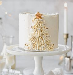 a white frosted cake with a christmas tree decoration on the top is sitting on a plate