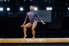 a woman standing on top of a balance beam