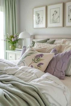 a bed with pillows and blankets on top of it next to pictures hanging above the headboard