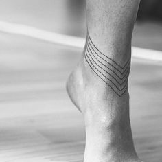 a black and white photo of a person's foot with an arrow tattoo on it