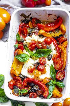 a white casserole dish filled with tomatoes and mozzarella