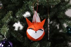 a paper fox ornament hanging from a christmas tree