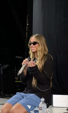 a woman sitting on a stage holding a microphone